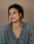Woman wearing a gray cardigan against a brown background