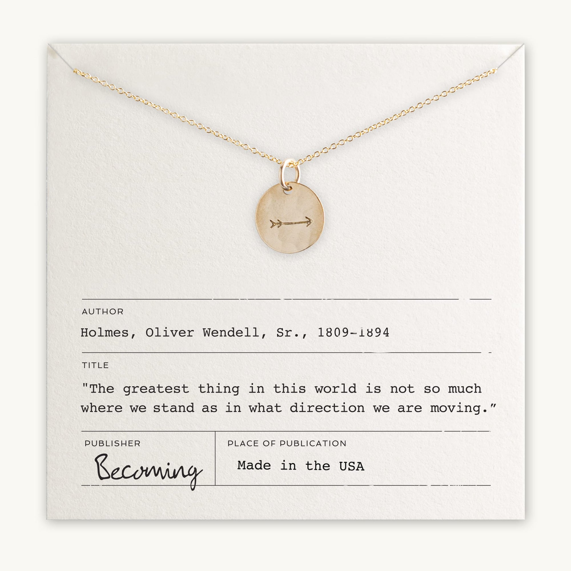 An Arrow Necklace from Becoming Jewelry features a gold arrow charm pendant, engraved and displayed on a card with a motivational quote attributed to Oliver Wendell Holmes, Sr. The necklace is made in the USA.
