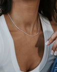 Close-up of someone in a white tank top wearing Becoming Jewelrys Curb Chain Necklace, with fingers resting on the collar.