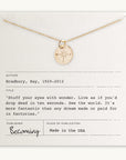 A gold Compass Necklace by Becoming Jewelry is displayed on a card that features an inspiring quote attributed to Ray Bradbury, encouraging wonder and travel. The card is labeled "Becoming," making this an ideal motivational gift, and it proudly states "Made in the USA.