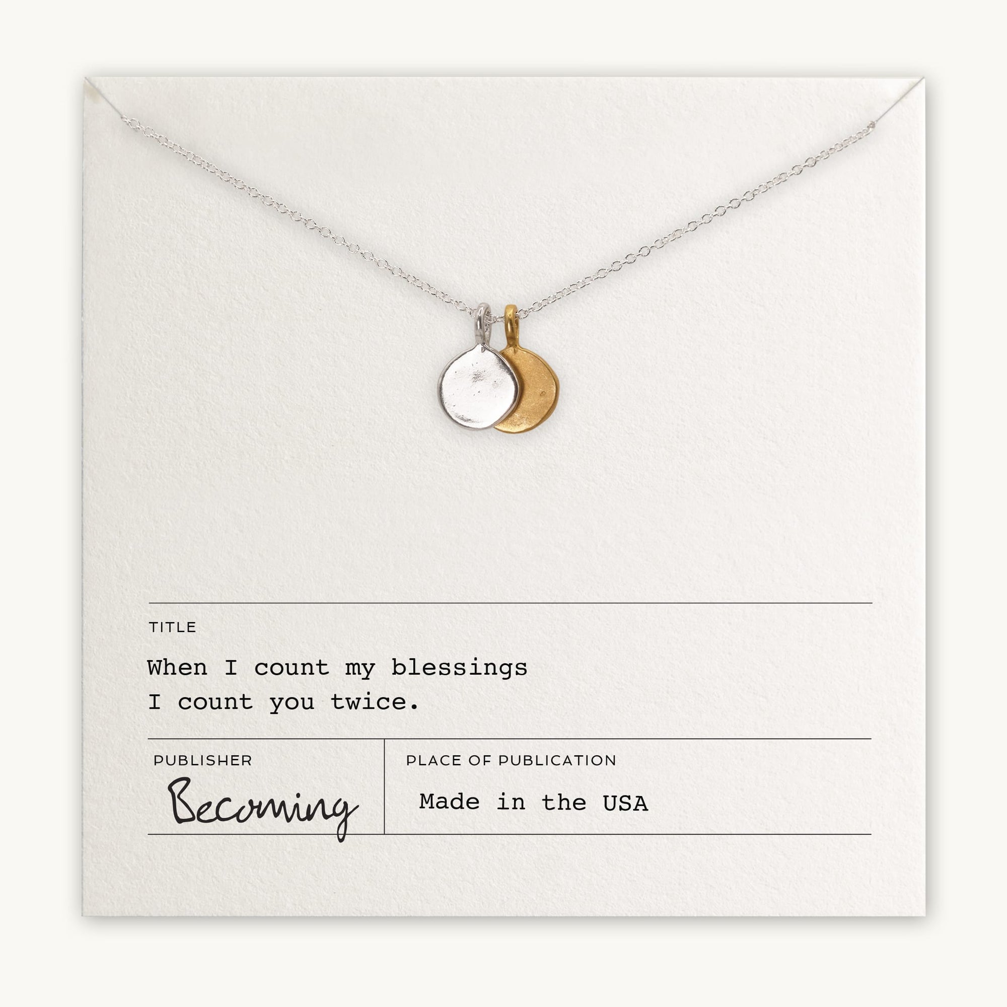 The "Count My Blessings Necklace" by Becoming Jewelry features a silver necklace with a round and crescent moon pendant, elegantly displayed on paper inscribed with the thoughtful phrase, "When I count my blessings, I count you twice," alongside other publication details. This charming gift pairs beautifully with silver drop discs.
