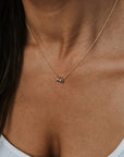 A person wearing the Friends Beads Necklace by Becoming Jewelry over a white tank top. This elegant, thin gold necklace with a small pendant and round beads is perfect for celebrating friendship, capturing the essence of cherished bonds in its simple yet sophisticated design.