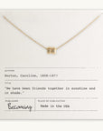The Friends Beads Necklace, a delicate gold piece adorned with a small pendant, is elegantly presented on a card that features Caroline Norton's quote, "We have been friends together in sunshine and in shade." Offered by Becoming Jewelry, this makes a meaningful gift for your dearest friends.