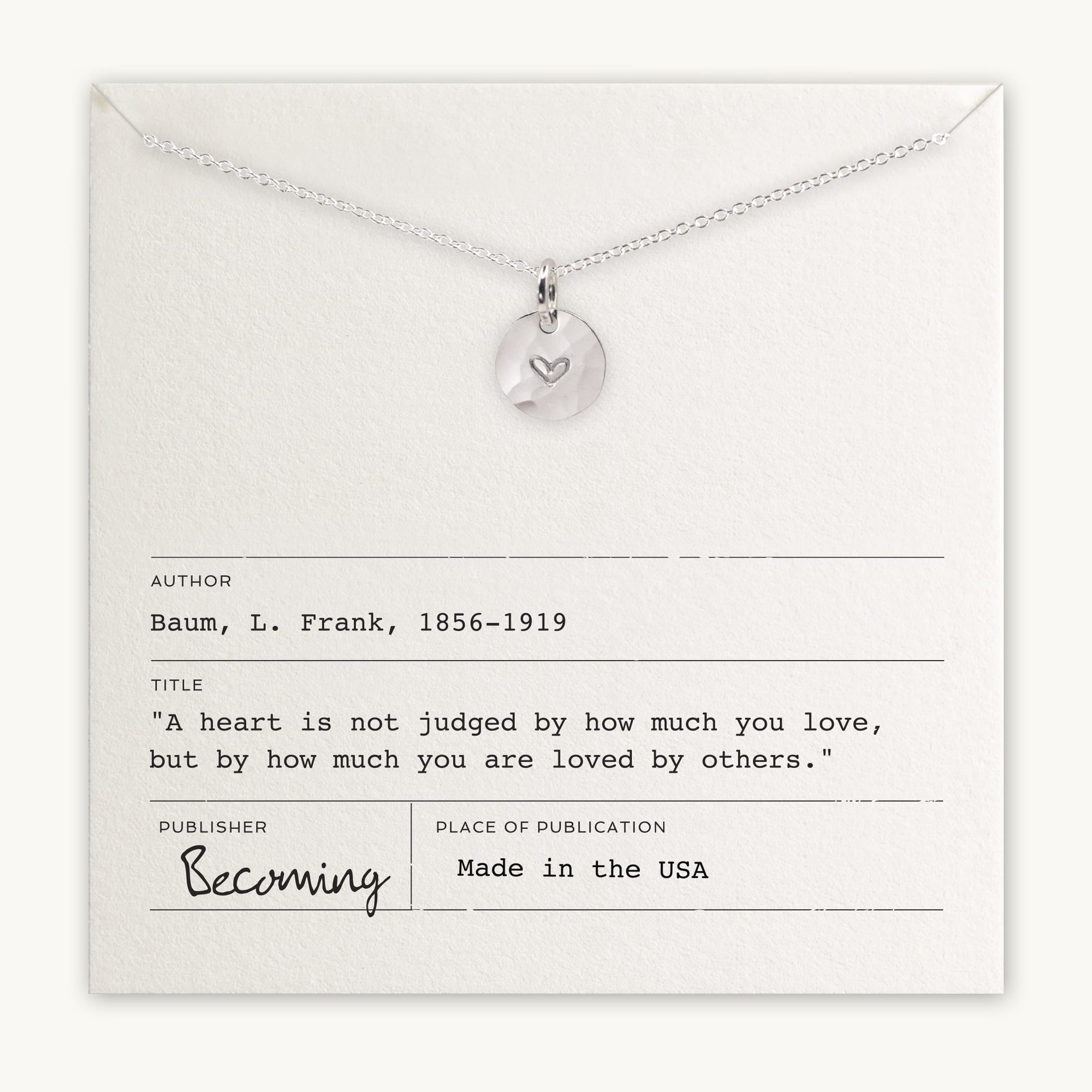 Silver heart charm pendant on a chain displayed on a card with an inspirational quote by L. Frank Baum from Becoming Jewelry&#39;s Heart Necklace.