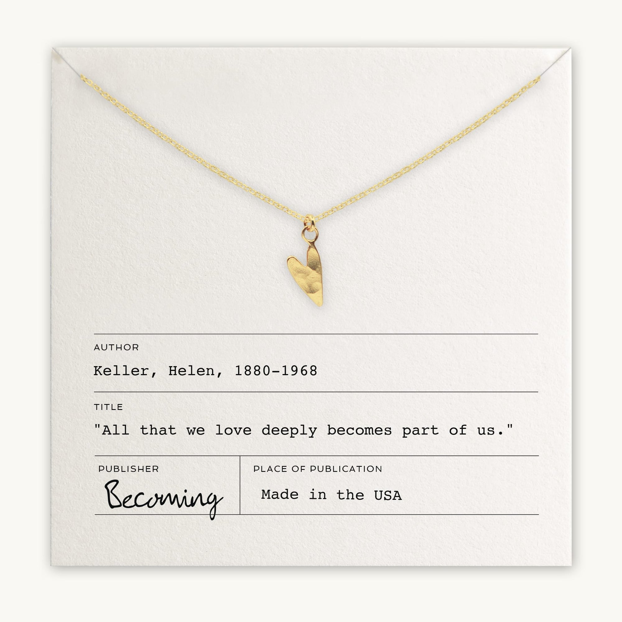 A gold heart charm on a chain rests atop an envelope containing Helen Keller's quote: "All that we love deeply becomes part of us." The publisher is listed as "Becoming Jewelry," and the Love Deeply Necklace serves as a precious token of this sentiment.