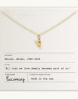 A gold heart charm on a chain rests atop an envelope containing Helen Keller's quote: "All that we love deeply becomes part of us." The publisher is listed as "Becoming Jewelry," and the Love Deeply Necklace serves as a precious token of this sentiment.