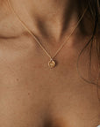 A woman wearing the Becoming Jewelry Heart Necklace with a gold heart-engraved pendant, perfect as a meaningful gift that is loved by others.