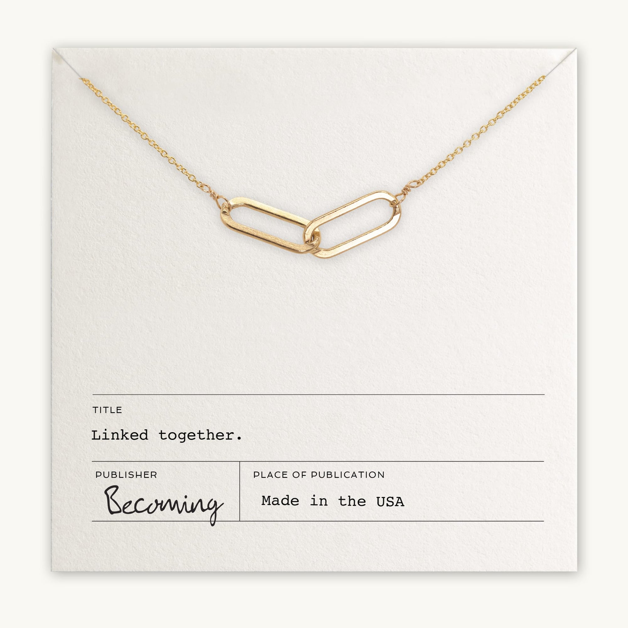 The Linked Together Necklace from Becoming Jewelry showcases a gold chain with two interwoven links and is beautifully presented on a card that reads "Linked together." Made in the USA, this exquisite piece symbolizes connection and unity, making it an ideal gift.