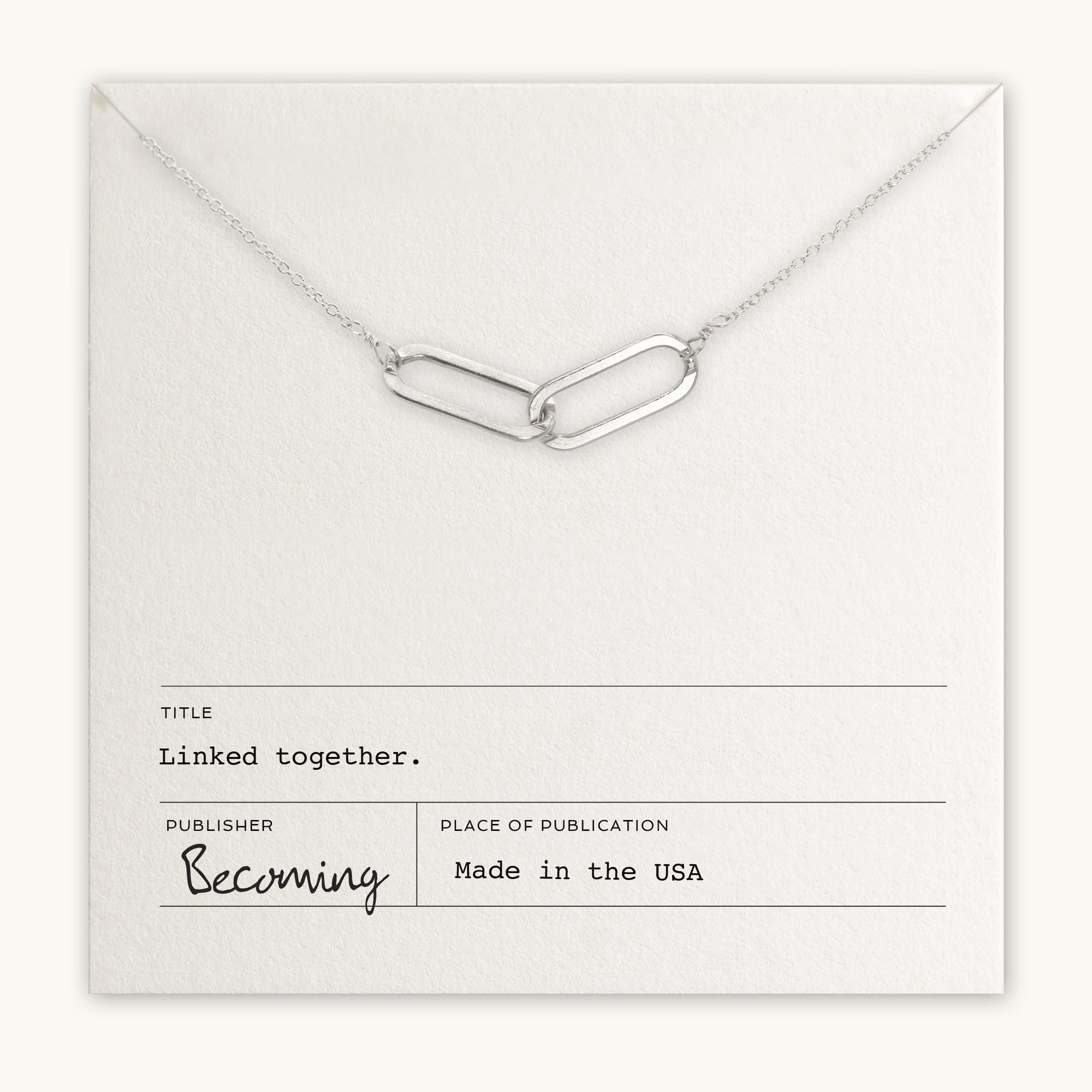 The "Linked Together Necklace" by Becoming Jewelry, a perfect gift, features two silver linked chain links displayed on a card that reads "Linked together" and is made in the USA.