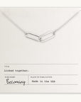The "Linked Together Necklace" by Becoming Jewelry, a perfect gift, features two silver linked chain links displayed on a card that reads "Linked together" and is made in the USA.