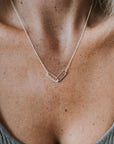 Close-up of a person wearing the Linked Together Necklace by Becoming Jewelry, a silver piece with a minimalist design resembling interlocking geometric shapes, symbolizing connection and making it an ideal gift.