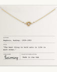 The Love Knot Necklace by Becoming Jewelry features a minimalist design with an intertwined small knot charm. It comes with a card quoting Audrey Hepburn: "The best thing to hold onto in life is each other." This timeless gift is made in the USA.