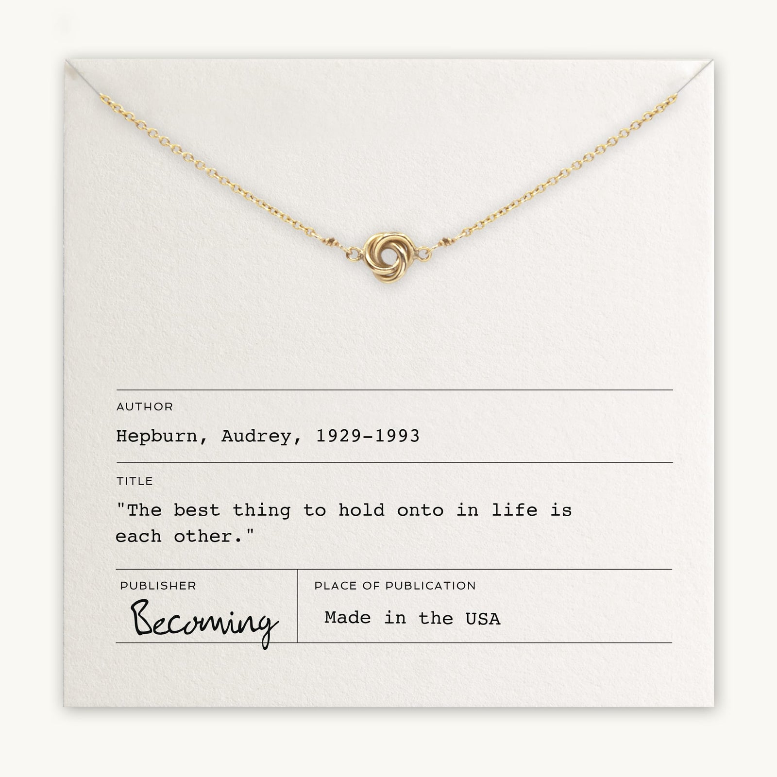 Becoming Jewelry's Love Knot Necklace with a knot pendant displayed on a card with an Audrey Hepburn quote.