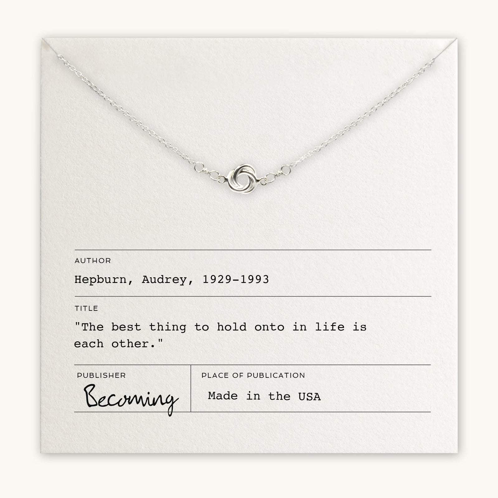 A Love Knot Necklace laid over a card with a quote by Audrey Hepburn, titled 
