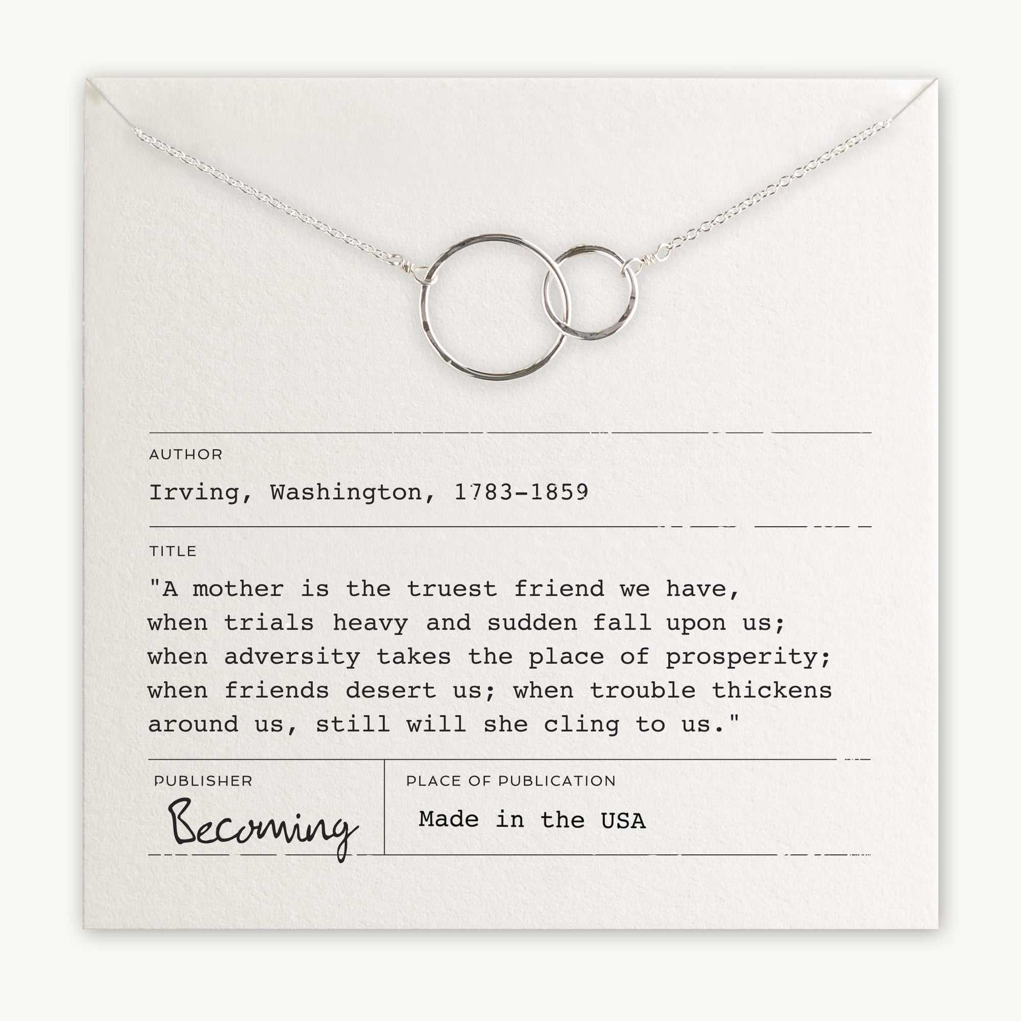 A silver necklace with two interlocking rings, symbolizing a special relationship, positioned over a card featuring a friendship quote by Washington Irving. The card notes "Publisher: Becoming Jewelry" and "Made in the USA." Perfect as the Mother Necklace to celebrate motherly love.