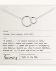 A silver necklace with two interlocking rings, symbolizing a special relationship, positioned over a card featuring a friendship quote by Washington Irving. The card notes "Publisher: Becoming Jewelry" and "Made in the USA." Perfect as the Mother Necklace to celebrate motherly love.