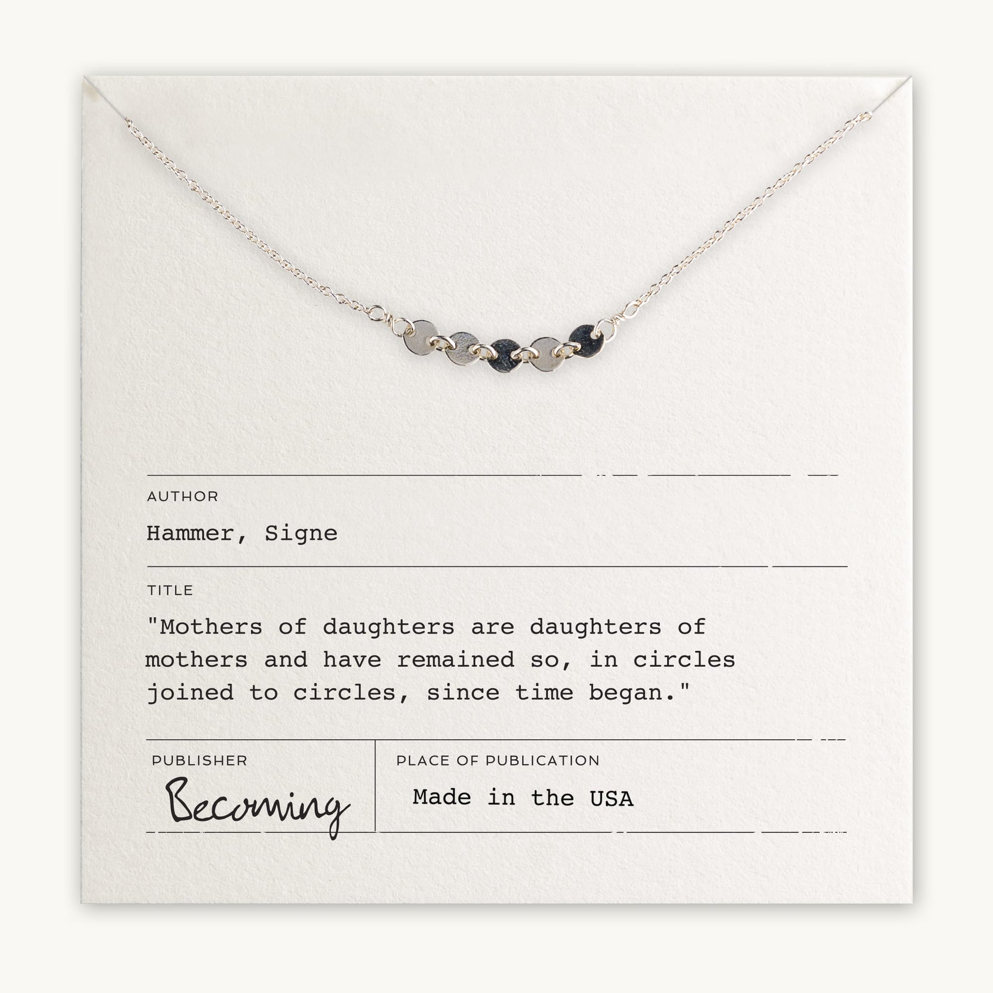 The delicate Mothers & Daughters Necklace, crafted by Becoming Jewelry and made in the USA, rests on a white card adorned with a poem by Signe Hammer celebrating the bond between mothers and daughters. This heartfelt gift is perfect for honoring that special woman in your life.