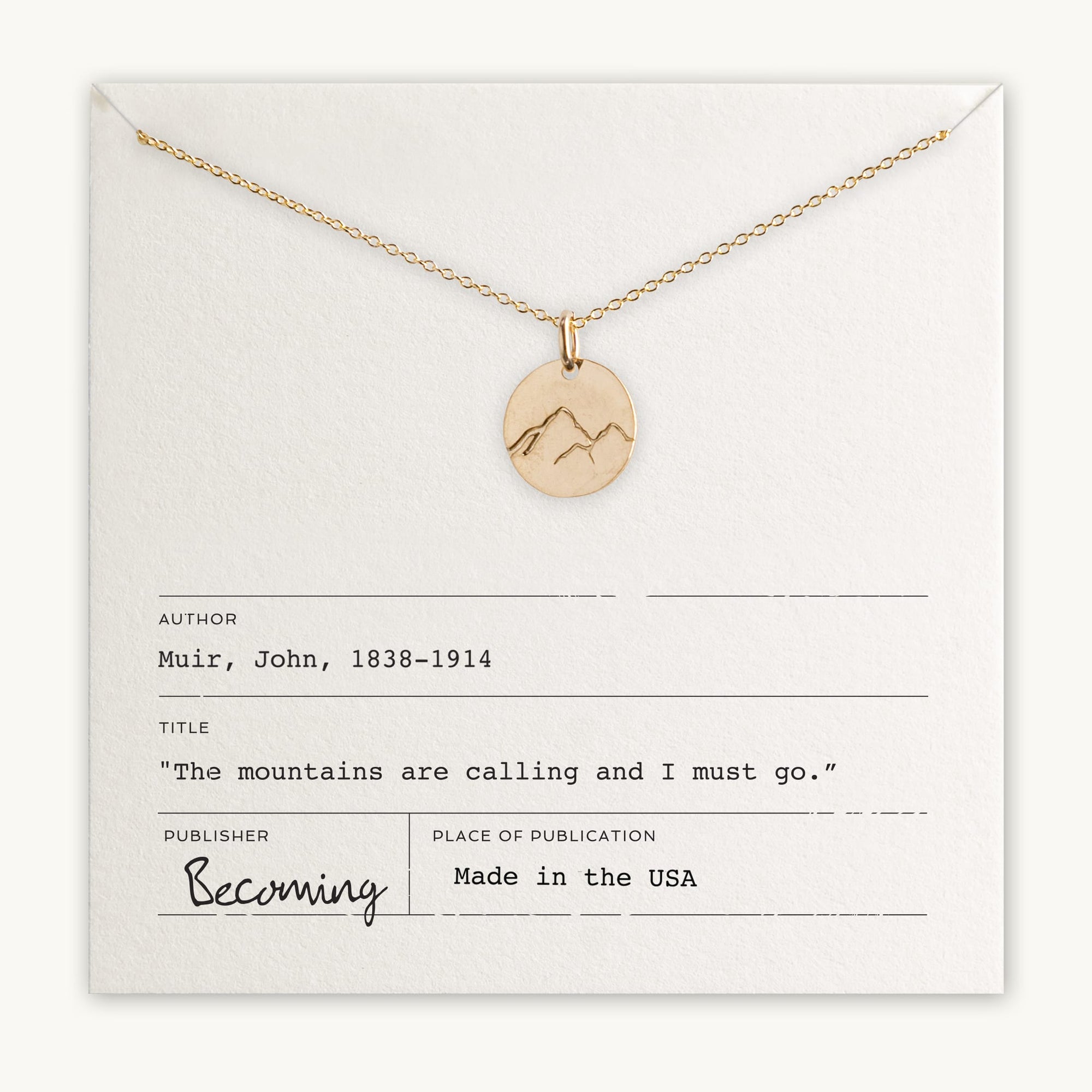 Becoming Jewelry's Mountains Are Calling Necklace pendant necklace with mountain charm displayed on a card with bibliographic-style information, including a quote, "the mountains are calling and I must go.