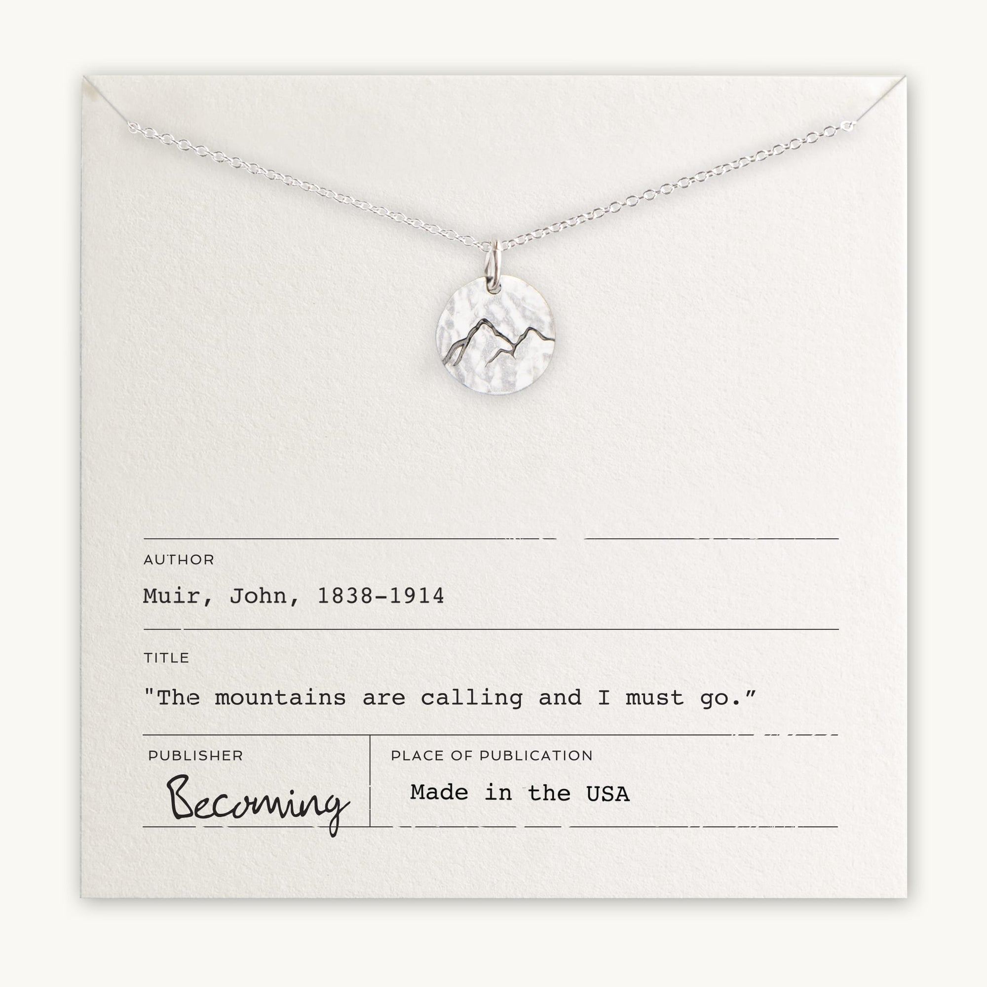A Becoming Jewelry Mountains Are Calling Necklace displayed on a card with a John Muir quote and labeled as "Made in the USA.