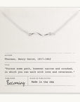 A Path Necklace with a curved path charm in gold filled displayed on a card featuring a quote by Henry David Thoreau, with the mention "becoming" and "made in the USA. (by Becoming Jewelry)
