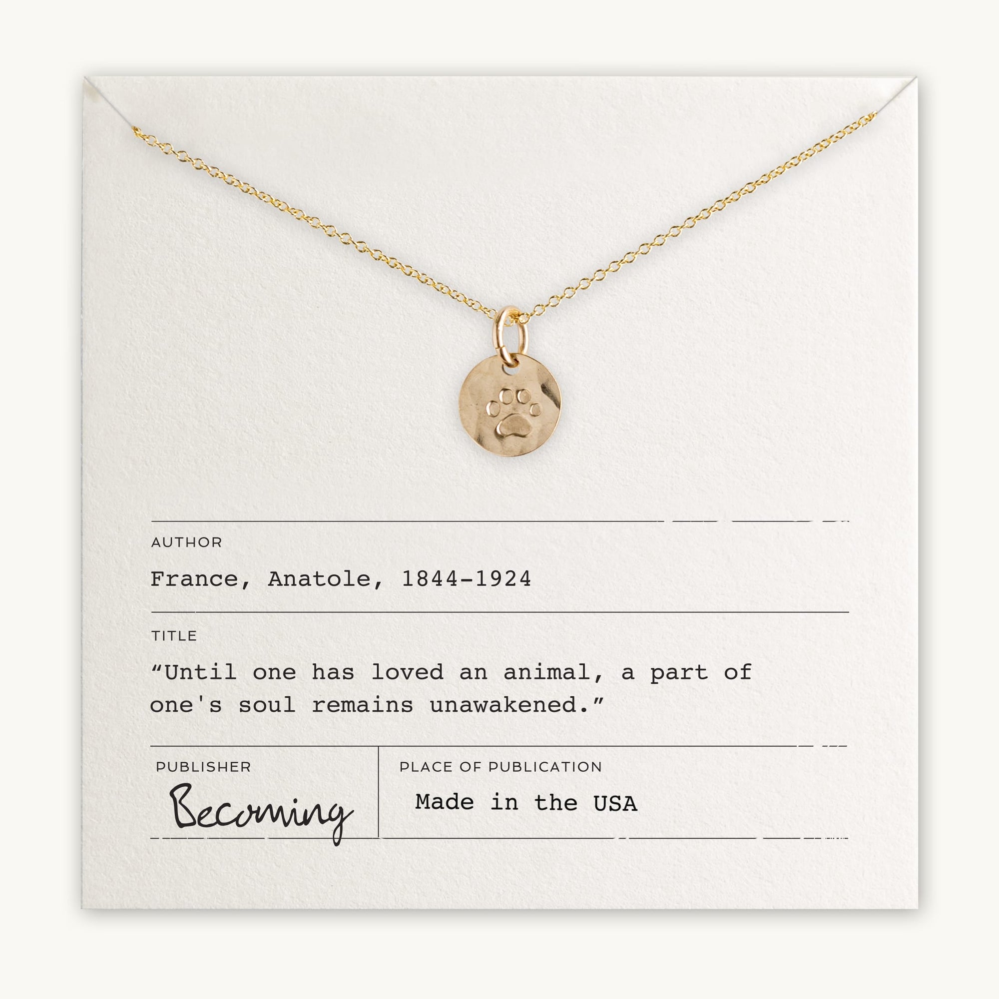 A gold Paw Print Necklace is presented on a card featuring a quote by Anatole France: "Until one has loved an animal, a part of one's soul remains unawakened." This lovely piece, published by Becoming Jewelry, makes for the perfect gift for any animal lover.