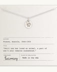The Paw Print Necklace by Becoming Jewelry is elegantly displayed on an off-white card that includes a quote from Anatole France about loving animals, details about the author, and proudly states "Made in the USA." This ideal gift for animal lovers perfectly captures the essence of adoration for our furry friends.