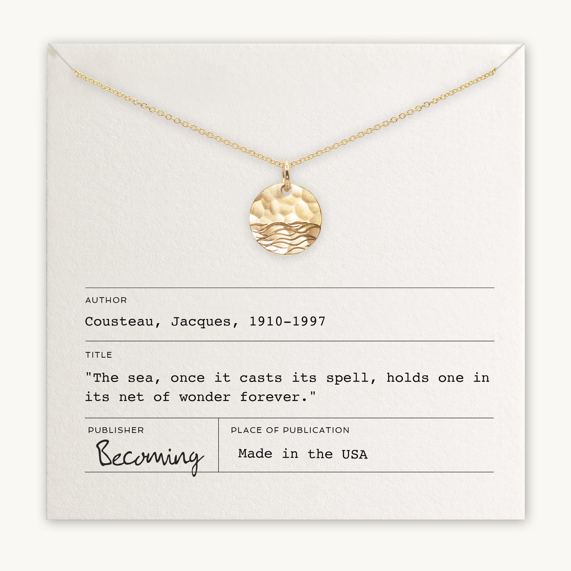 Introducing "The Sea Necklace" by Becoming Jewelry: a gold necklace adorned with a wave-patterned pendant, elegantly displayed on a card featuring Jacques Cousteau's inspiring quote, "The sea, once it casts its spell, holds one in its net of wonder forever." Proudly made in the USA, this ocean-inspired treasure makes an enchanting gift for anyone mesmerized by the magic of the sea.
