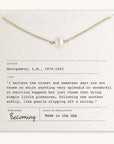 The Simple Pleasures Pearl Necklace by Becoming Jewelry features a delicate gold chain with a single pearl and is elegantly presented on a card that includes a quote by L.M. Montgomery, details about the author, and publication information. The design effortlessly captures timeless beauty.