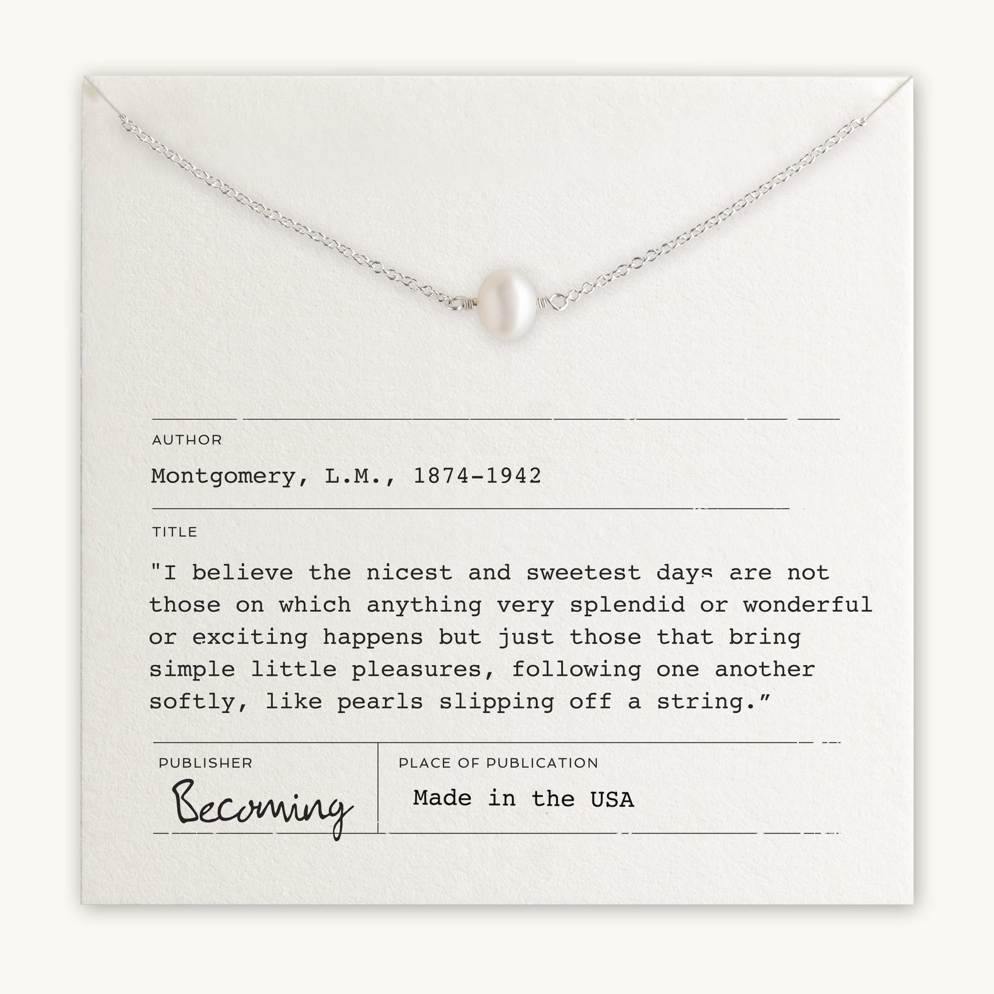 The Simple Pleasures Pearl Necklace by Becoming Jewelry, crafted with a silver chain and a single pearl pendant, is elegantly presented on a card featuring a quote from L.M. Montgomery along with the publication details. This exquisite piece showcases timeless beauty and proudly states it is "Made in the USA.