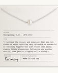 The Simple Pleasures Pearl Necklace by Becoming Jewelry, crafted with a silver chain and a single pearl pendant, is elegantly presented on a card featuring a quote from L.M. Montgomery along with the publication details. This exquisite piece showcases timeless beauty and proudly states it is "Made in the USA.