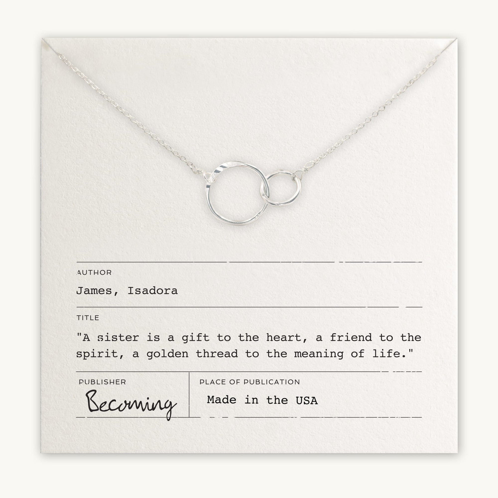 The Sisters Necklace by Becoming Jewelry is a stunning silver necklace featuring intertwined circles, elegantly placed on a card that reads, "A sister is a gift to the heart, a friend to the spirit, a golden thread to the meaning of life.