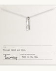 A silver necklace, a best-selling gift from Becoming Jewelry, is displayed on a card reading: Title: Through Thick & Thin. Publisher: Becoming Jewelry. Made in the USA.