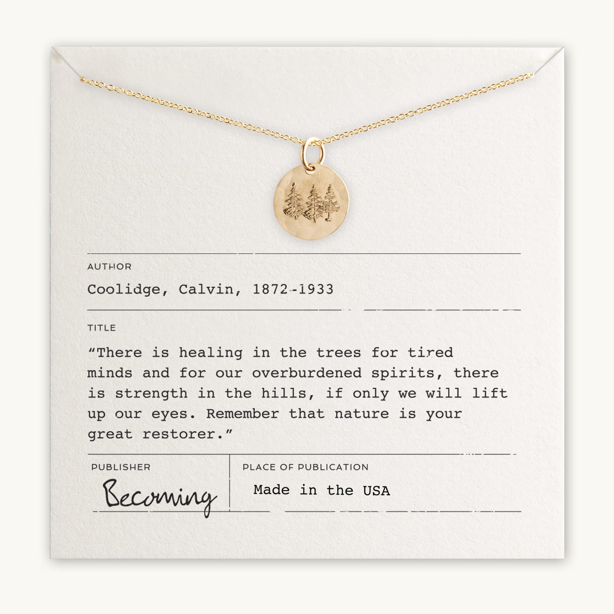 A gold Trees Necklace by Becoming Jewelry, featuring a pendant with engraved trees, is presented on a card that includes a quote by Calvin Coolidge about nature's restorative power. The card bears publication details from Becoming.