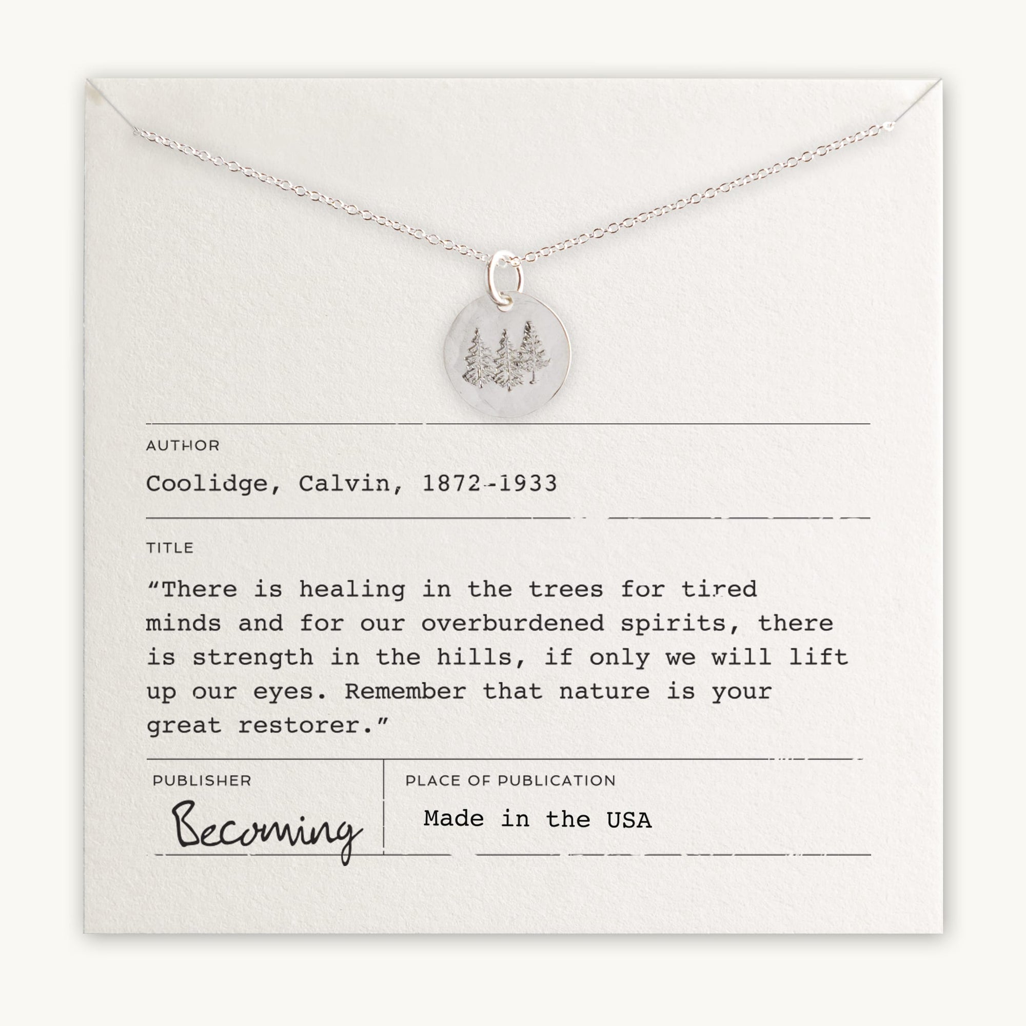 Description: A Trees Necklace from Becoming Jewelry, featuring a silver tree pendant. The necklace is displayed on a card that includes a quote by Calvin Coolidge about the healing power of nature and details such as "Made in the USA." This piece celebrates the restoration offered by nature.