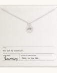 The bestselling You Are My Sunshine Necklace from Becoming Jewelry features a radiant sun charm and is presented on a cream card with the messages "You are my sunshine" and "Becoming, Made in the USA." This silver gift eloquently conveys love and warmth.