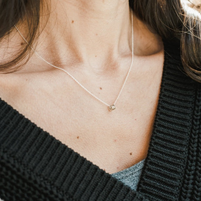 A woman wears a delicate Becoming Jewelry Blessings Necklace with a small pendant, the focus is on her neckline and the jewelry.
