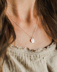 A close-up of a woman wearing a delicate You Are My Sunshine Necklace by Becoming Jewelry with a small, round sunshine charm pendant.