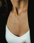 A person wearing the Becoming Jewelry Love You To The Moon Necklace with a crescent moon pendant, a white top, and a black cardigan; it's a meaningful piece that serves as a daily reminder of love.