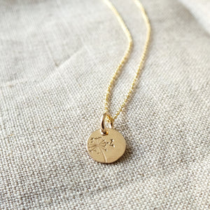 Becoming Jewelry's Dandelion Wishes Necklace features a round pendant with a dandelion design on a textured fabric.