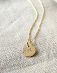 Becoming Jewelry's Dandelion Wishes Necklace features a round pendant with a dandelion design on a textured fabric.