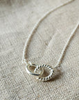 Linked By Blood Necklace with a circular pendant on a textured fabric surface by Becoming Jewelry.