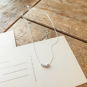 My Wish For You Necklace by Becoming Jewelry with bead details displayed on a wooden surface next to a message card.