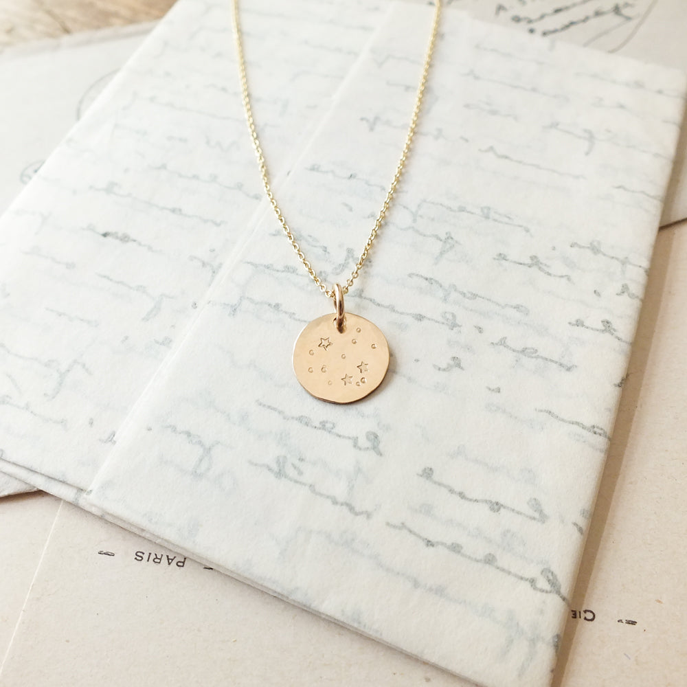 Watch the Stars Necklace&quot; by Becoming Jewelry with embossed design displayed on a piece of textured paper.