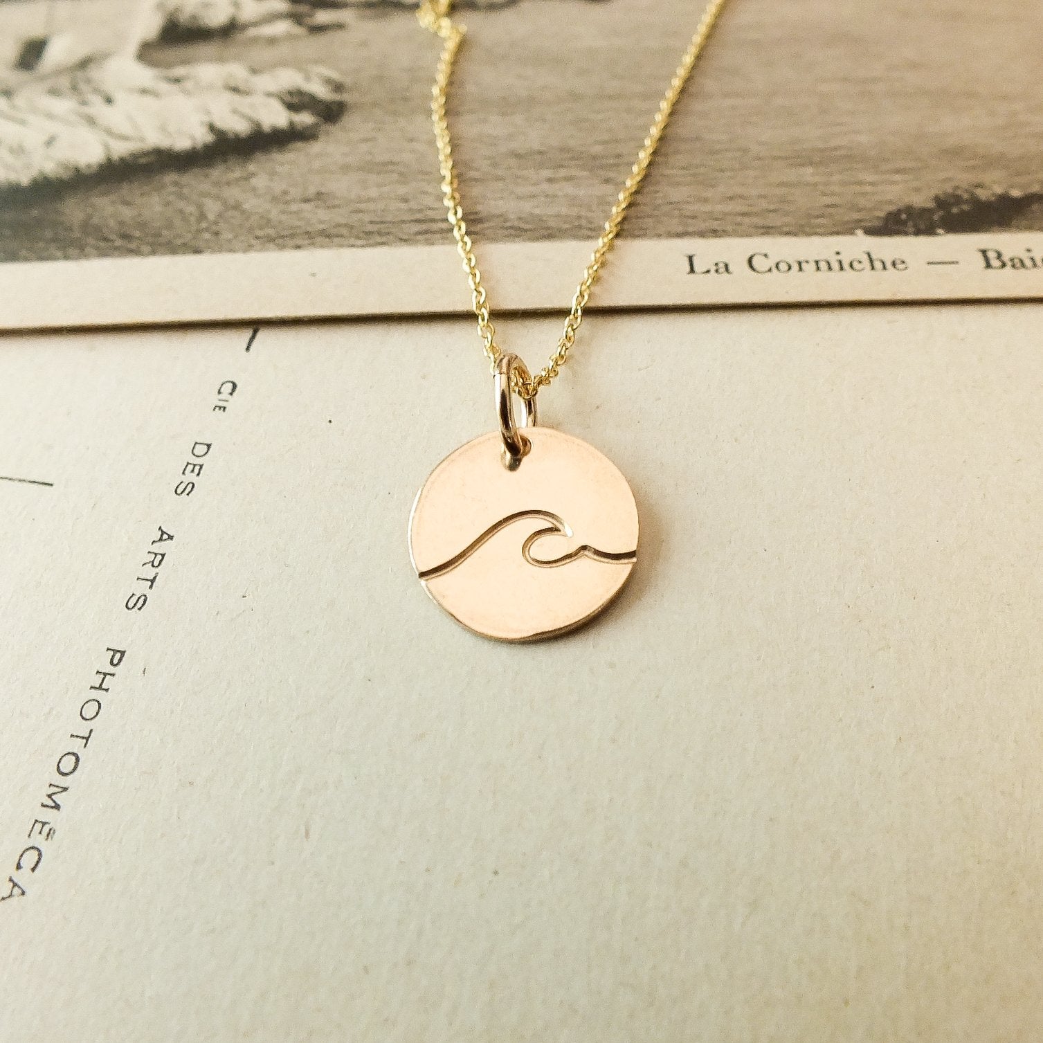 Wave Round Charm Necklace by Becoming Jewelry displayed on a book page.