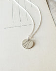 River Necklace by Becoming Jewelry with a minimalist leaf design displayed on a plain background.