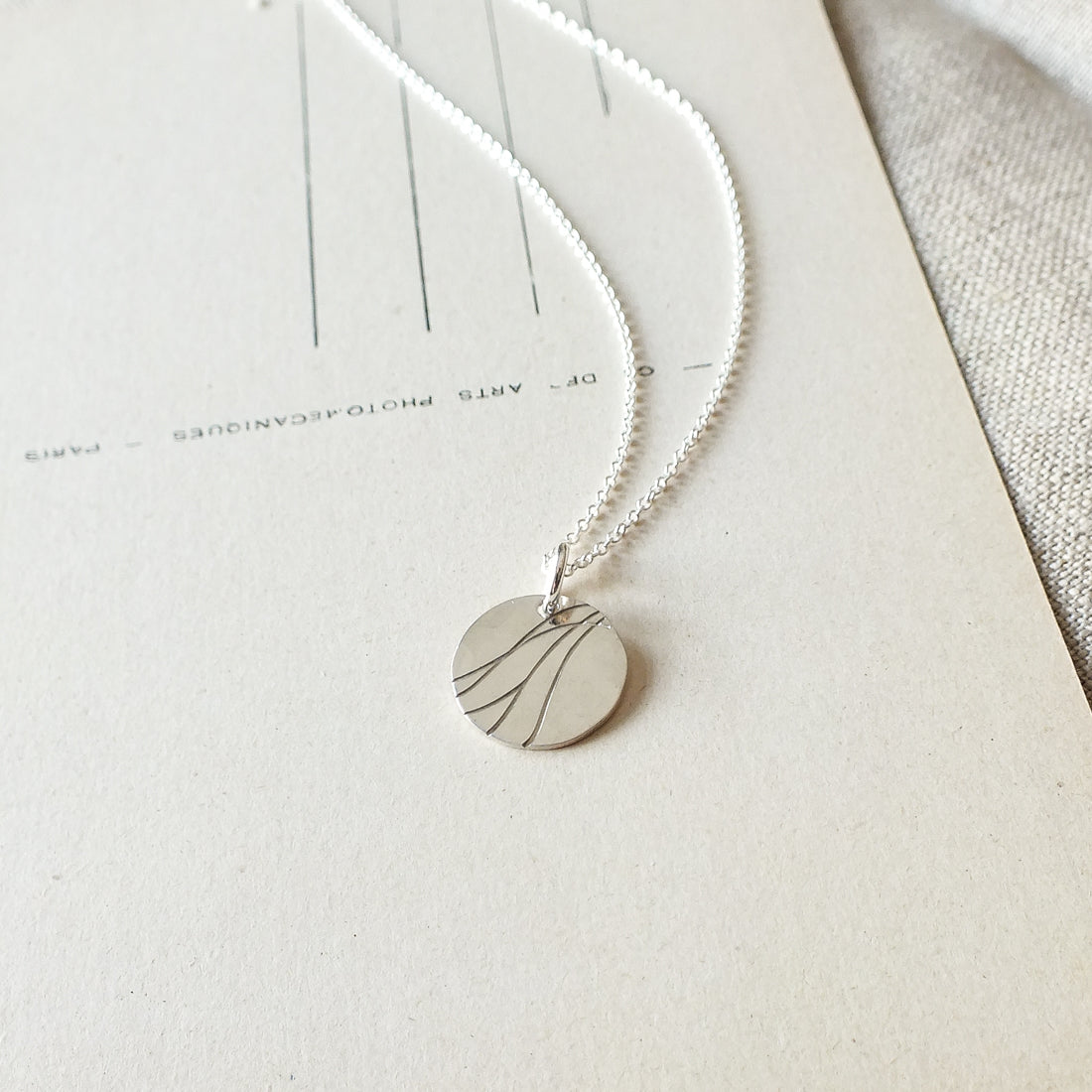 River Necklace by Becoming Jewelry with a minimalist leaf design displayed on a plain background.