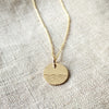 The Sea Necklace by Becoming Jewelry filled pendant with engraved waves on a textured fabric background.