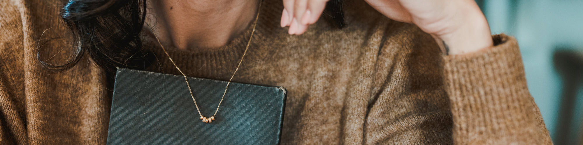 A close-up view of a person wearing a simple bar pendant necklace.