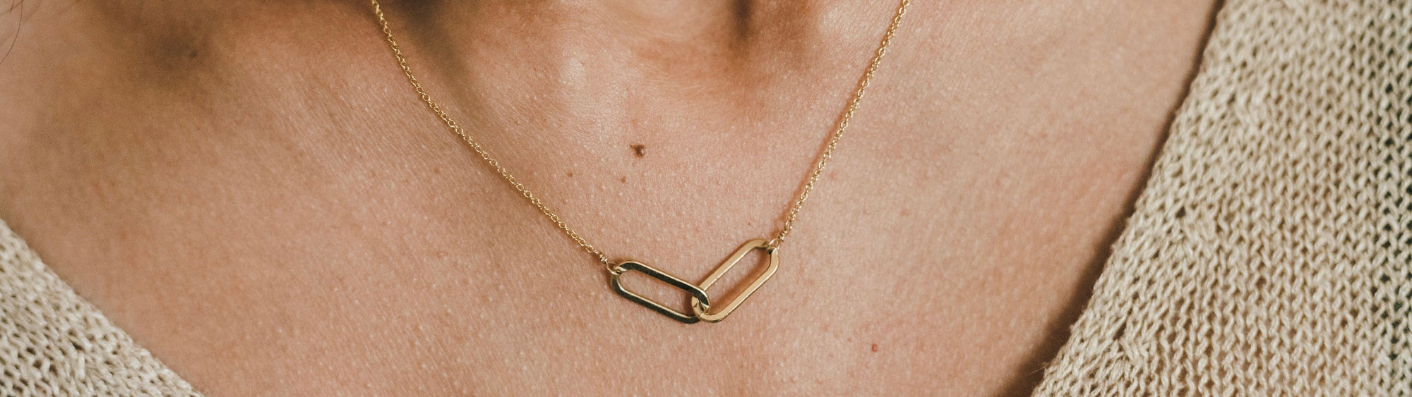 Gold musical note pendant on a necklace against a person's neckline.