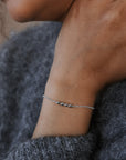 Close-up of a person wearing a bracelet on a gray sweater